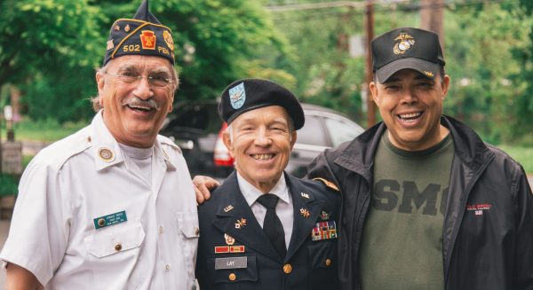 three men of different ages wearing military attire smile for the camera 